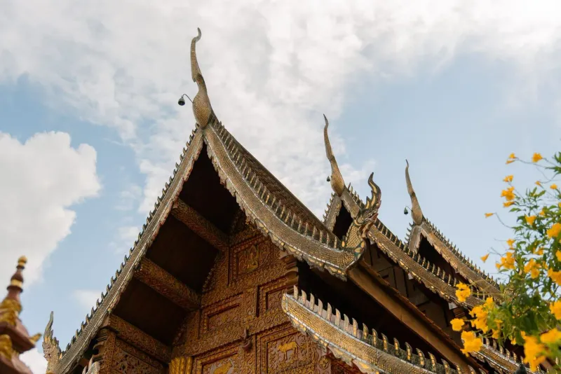 Ornate temple roof with traditional Thai architecture under a clear sky in Chiang Mai