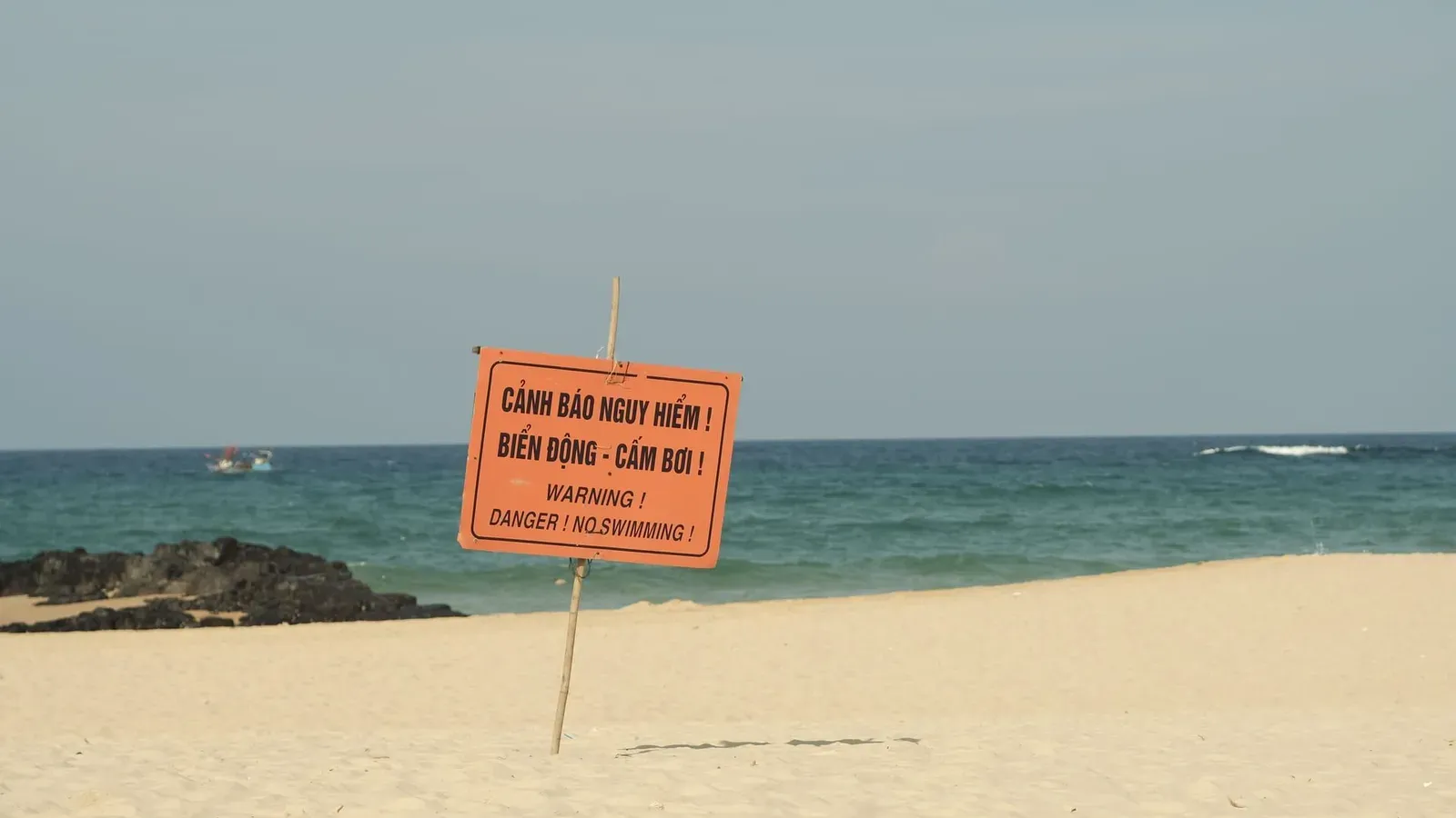 No swimming warning sign on a sandy tropical beach comparable to unguarded stretches of Koh Samui