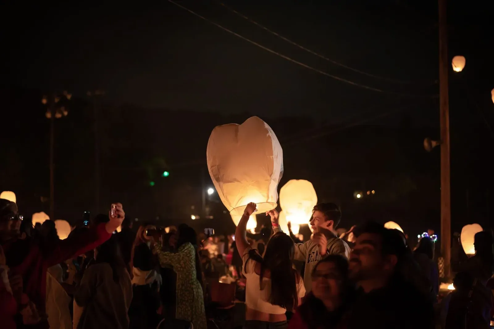 People gathered under a lantern-lit night sky at a festival, similar to Loy Krathong celebrations on Koh Samui's Chaweng Beach