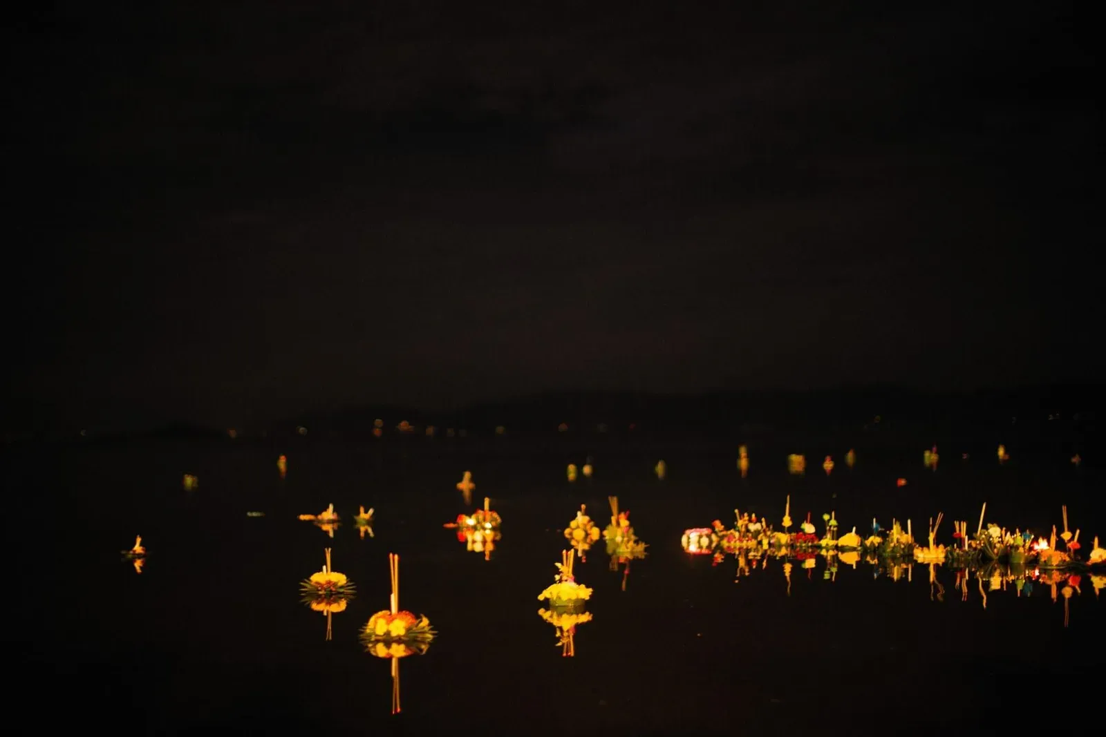 Floating lanterns illuminating a calm bay at night, evoking the evening events during Koh Samui's Samui Regatta sailing week
