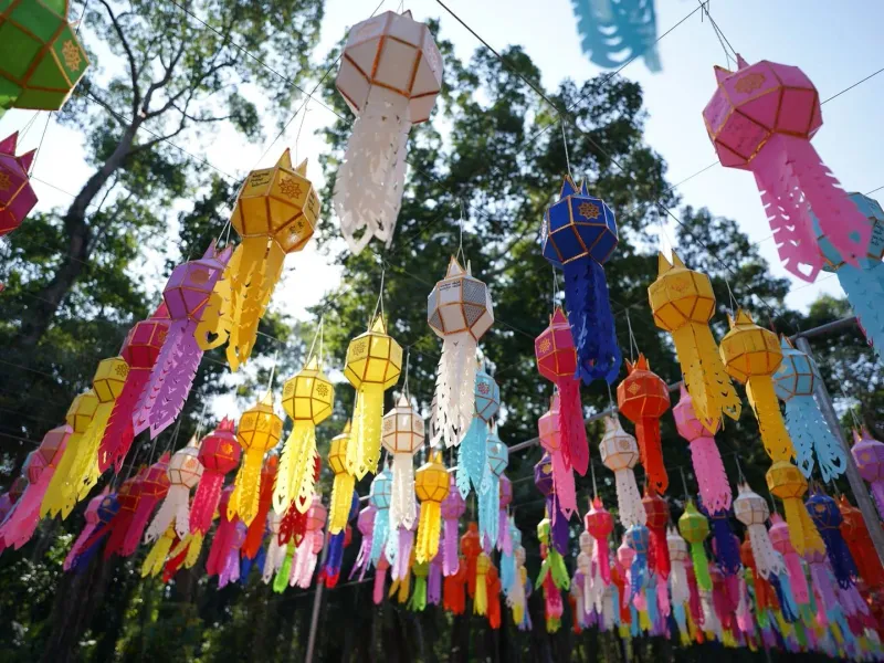 Colorful paper lanterns hanging outdoors at a Thai festival under daylight, similar to Vegetarian Festival decorations on Koh Samui