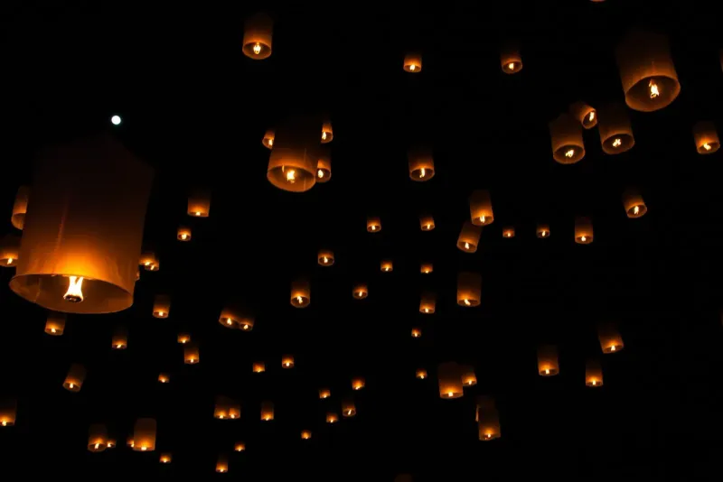 Sky lanterns floating against a dark night sky during a traditional Thai festival near Koh Samui