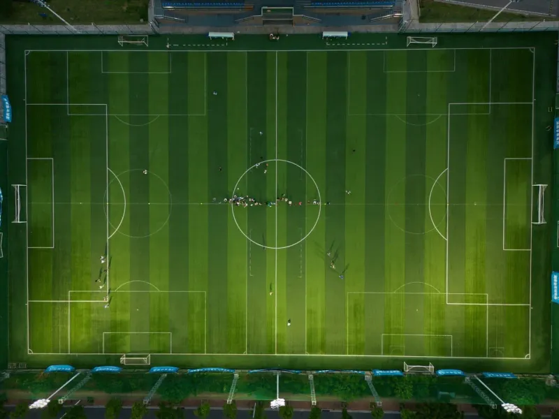 Aerial view of a full-size football pitch with players scattered across the grass during a match
