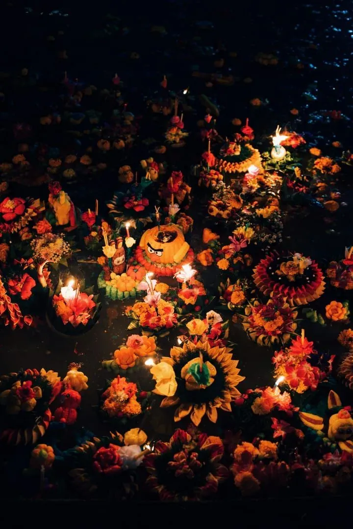 Vibrant floating flower and candle arrangements marking a Buddhist holiday festival in Thailand