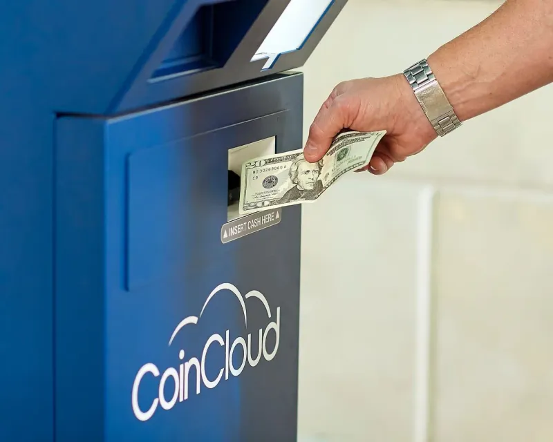 Hand inserting Thai baht cash into an ATM machine on Koh Samui