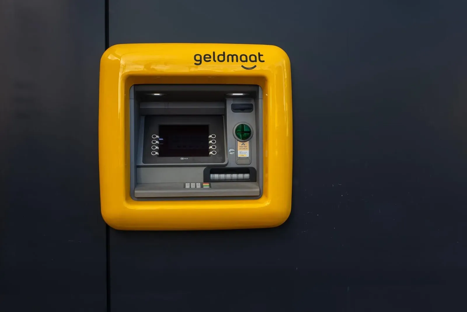 Bright yellow ATM machine mounted on a wall for cash withdrawals in Thailand