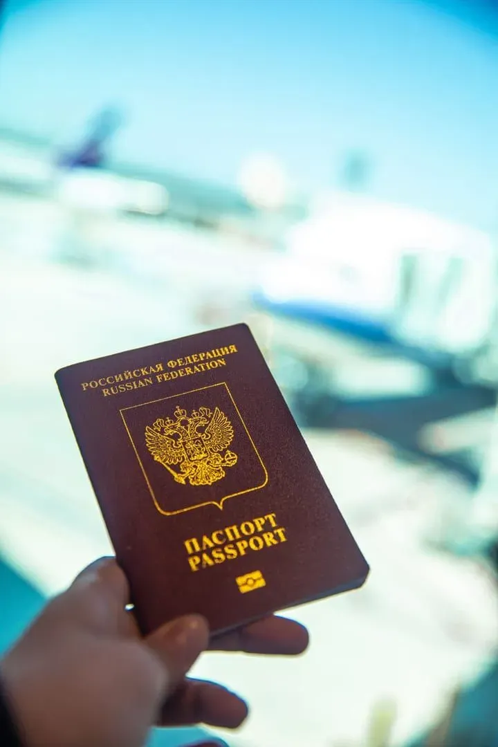Passport held near an airport gate window before a flight to Koh Samui, Thailand