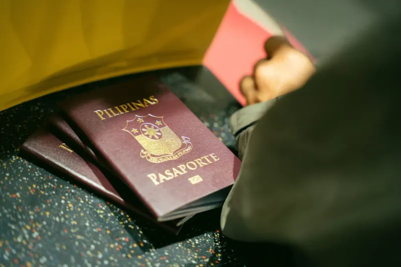 Close-up of passports held together at an airport ahead of a Thailand immigration counter