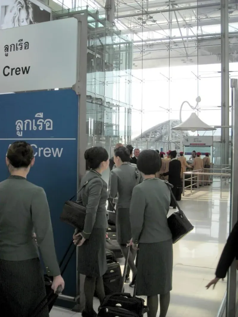 Airline crew queuing at an immigration bureau counter inside a Thailand international airport