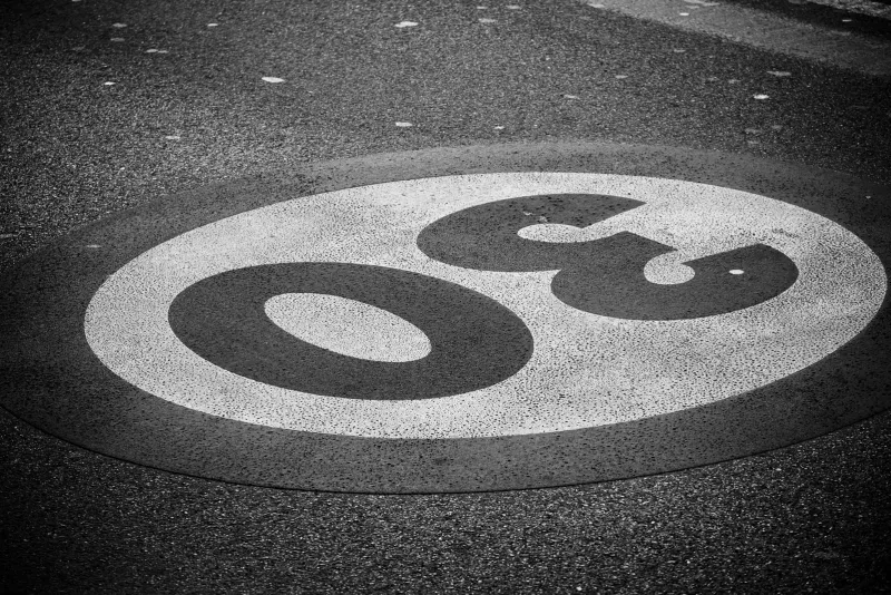 Panneau rond de limitation à 50 km/h sur un poteau au milieu de la végétation, en bord de route en Thaïlande