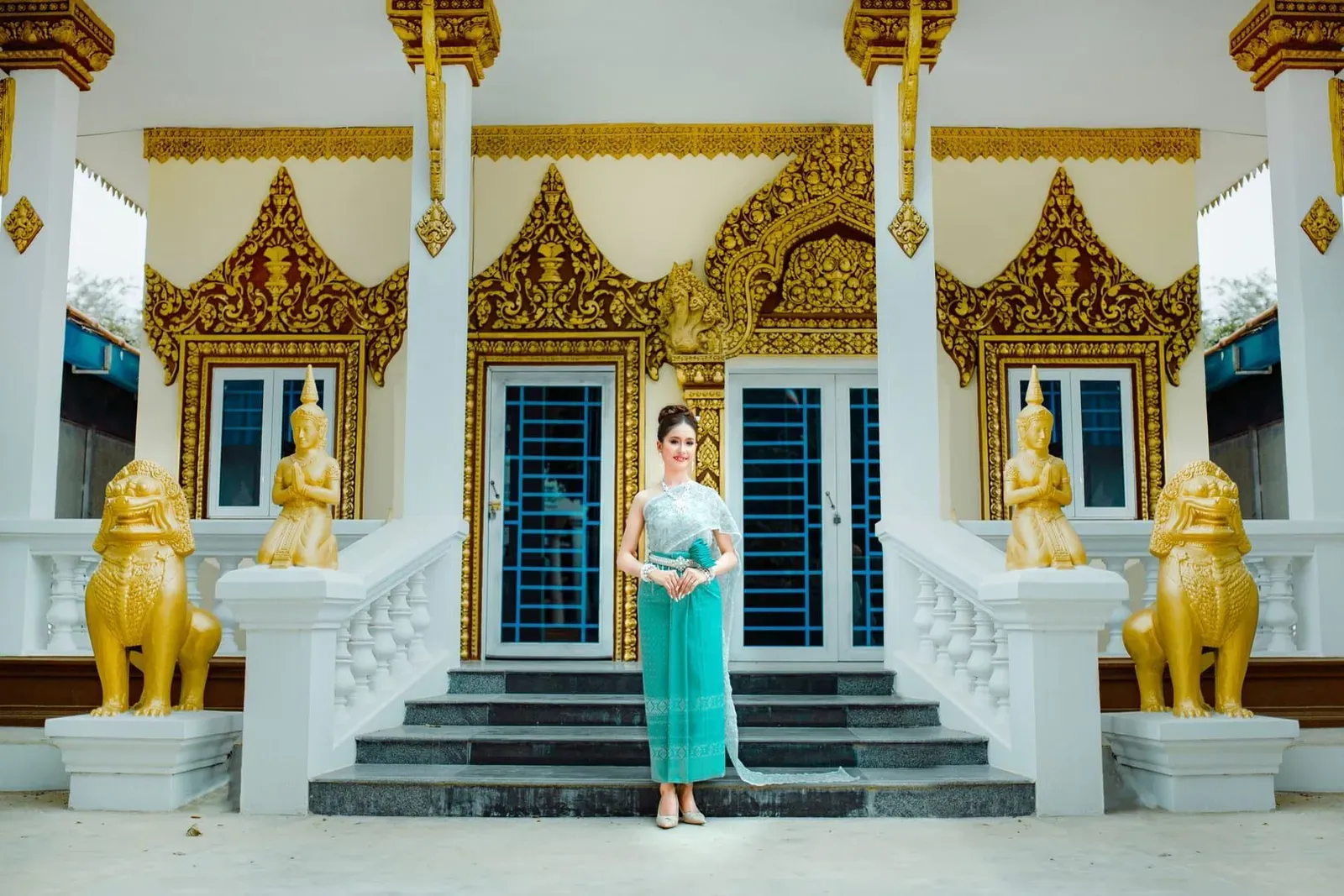 Visitor in modest traditional dress standing at an ornate Thai temple entrance in Koh Samui