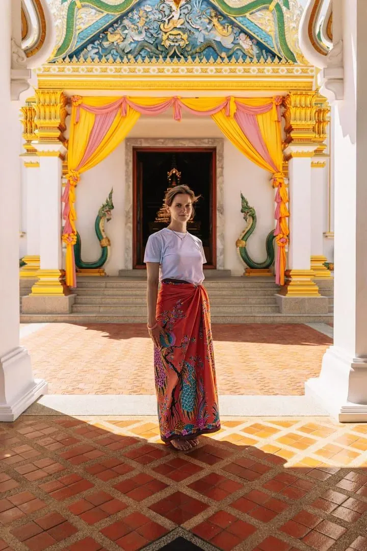 Woman in modest Thai dress standing at a temple entrance in Thailand