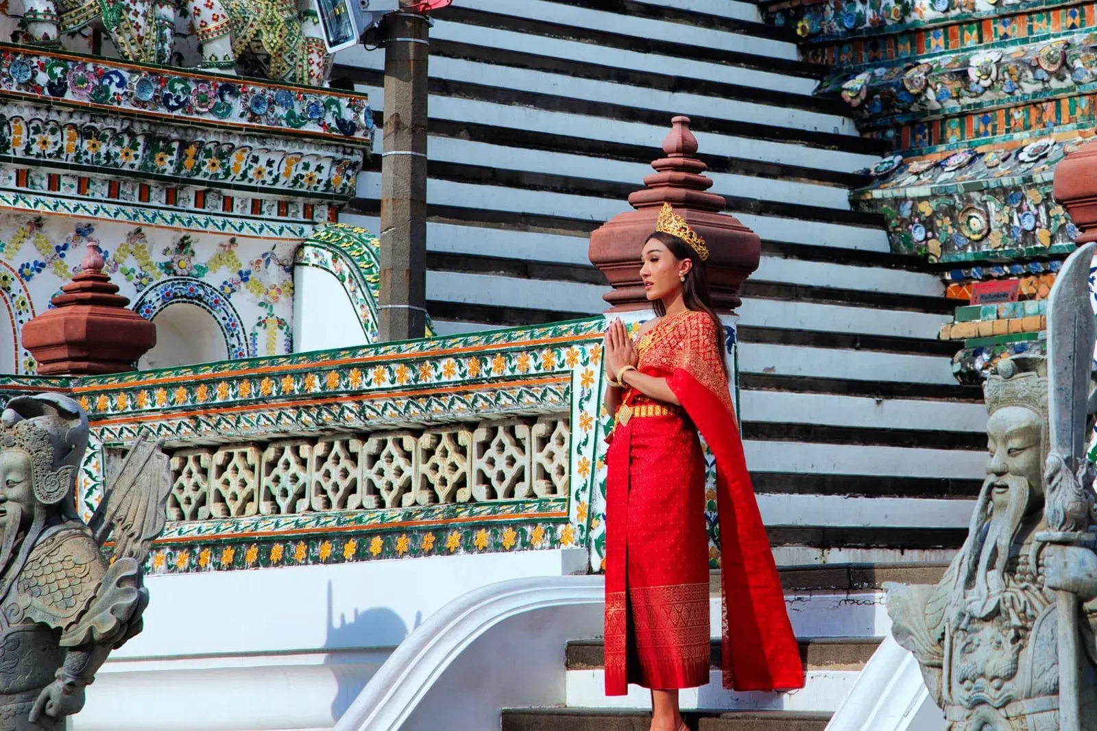 Visitor in traditional attire making an offering at a Buddhist temple altar in Thailand