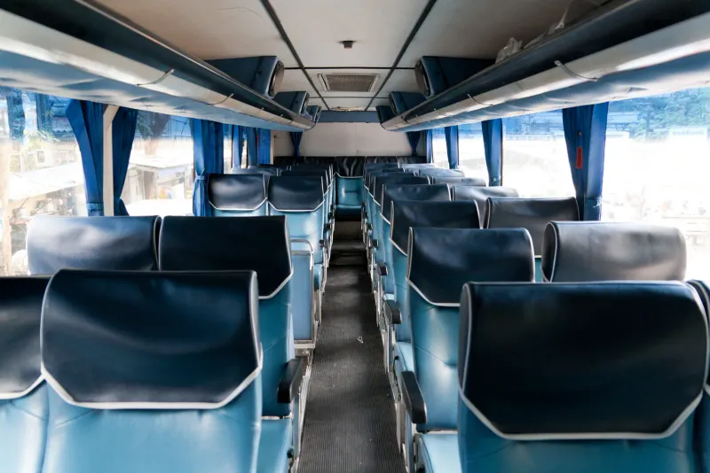 Intérieur d'un autocar interurbain en Thaïlande, rangées de sièges inclinables bleus et rideaux