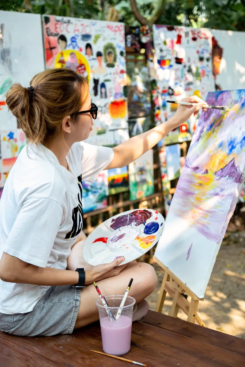 Un artista al cavalletto che mescola i colori all'aperto
