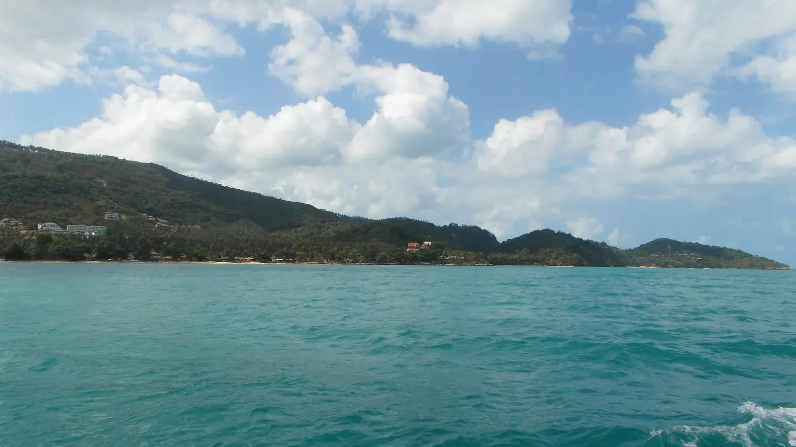 Koh Samui's forested interior hills running along the coast, seen from the water near the island's northwest tip
