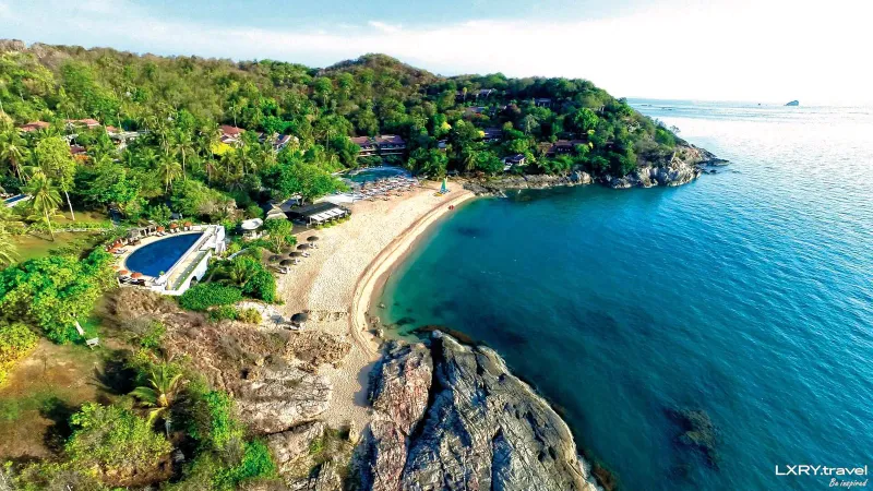 Luftaufnahme der geschwungenen Bucht von Tong Sai Bay mit Pool und Resortgebäuden am Hang