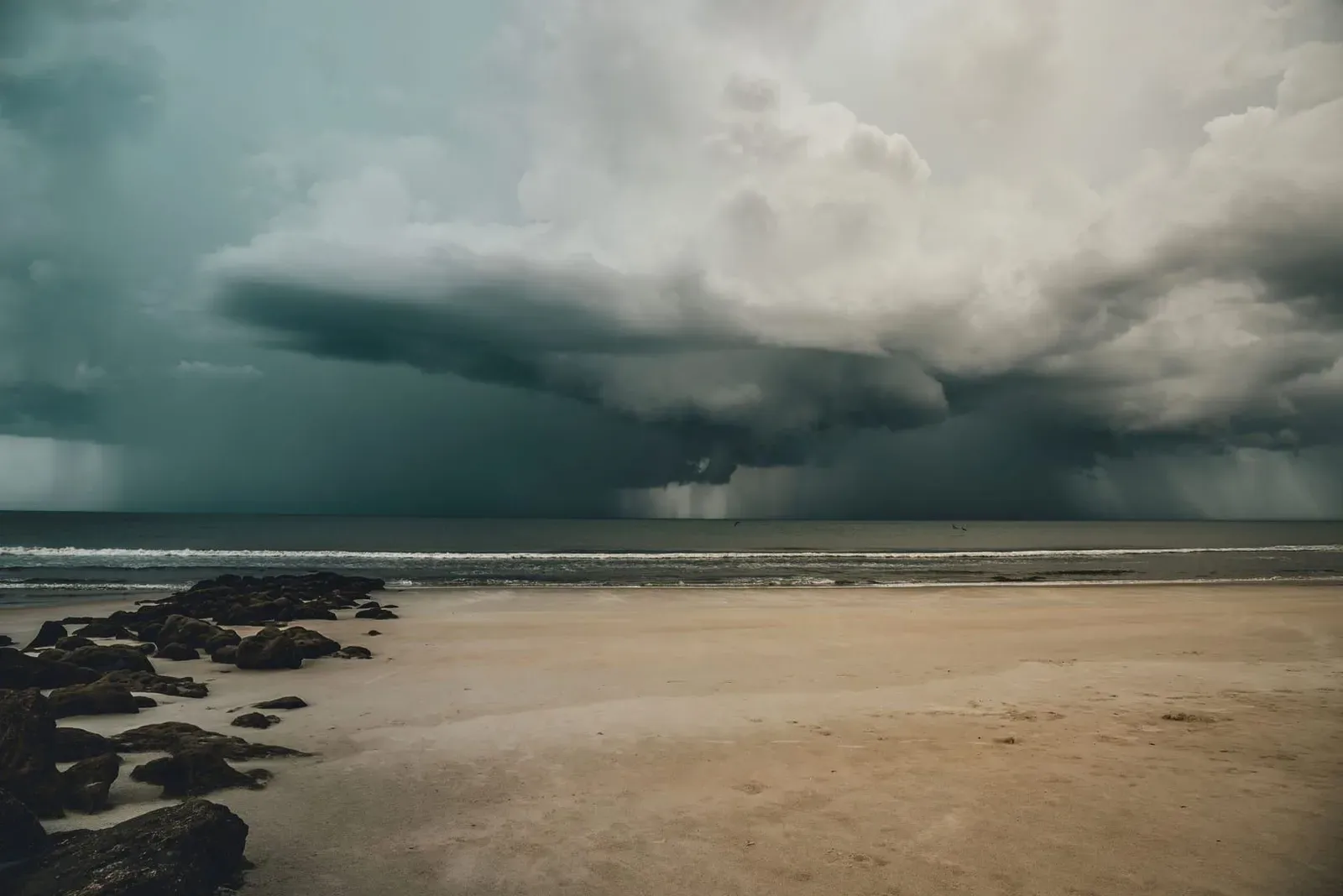 Storm clouds gathering over a quiet, empty sandy beach on Koh Samui in the rainy season