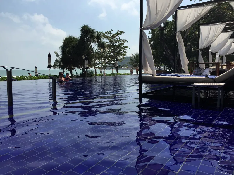Piscine infinity de Vana Belle avec lits balinais à l'ombre et parasols face à la mer à Koh Samui