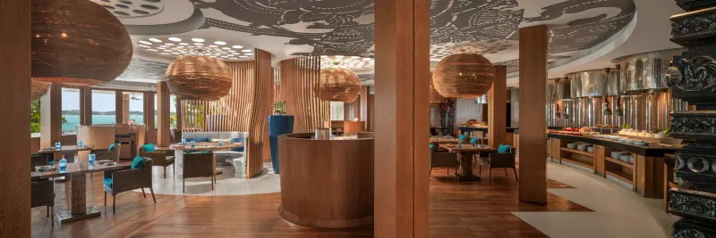 Intérieur du restaurant The Kitchen Table du W Koh Samui, avec plafond à motifs, lampes en rotin et buffet