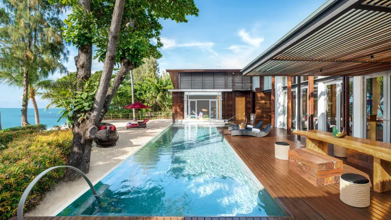 Piscine en longueur et terrasse en bois d'une villa du W Koh Samui, avec la mer à gauche