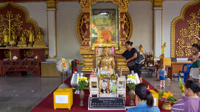 Visitors praying before a golden bust statue of the monk inside the memorial hall