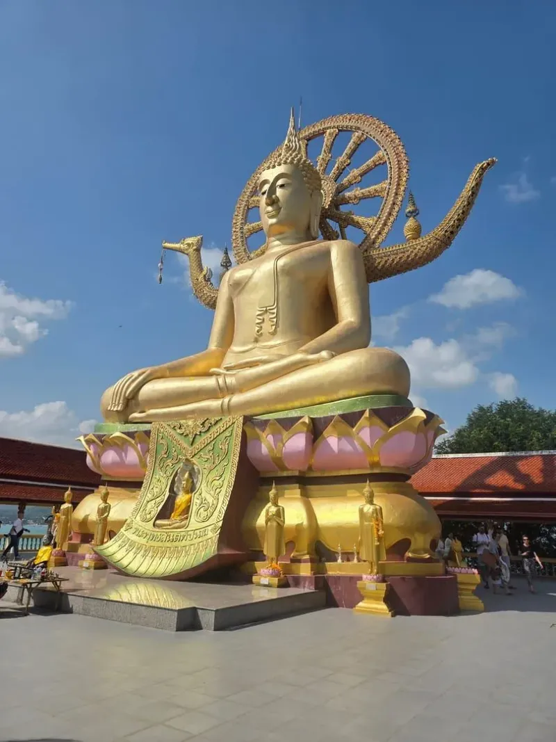 Golden Big Buddha statue with dharma wheel backdrop at Wat Phra Yai Koh Samui