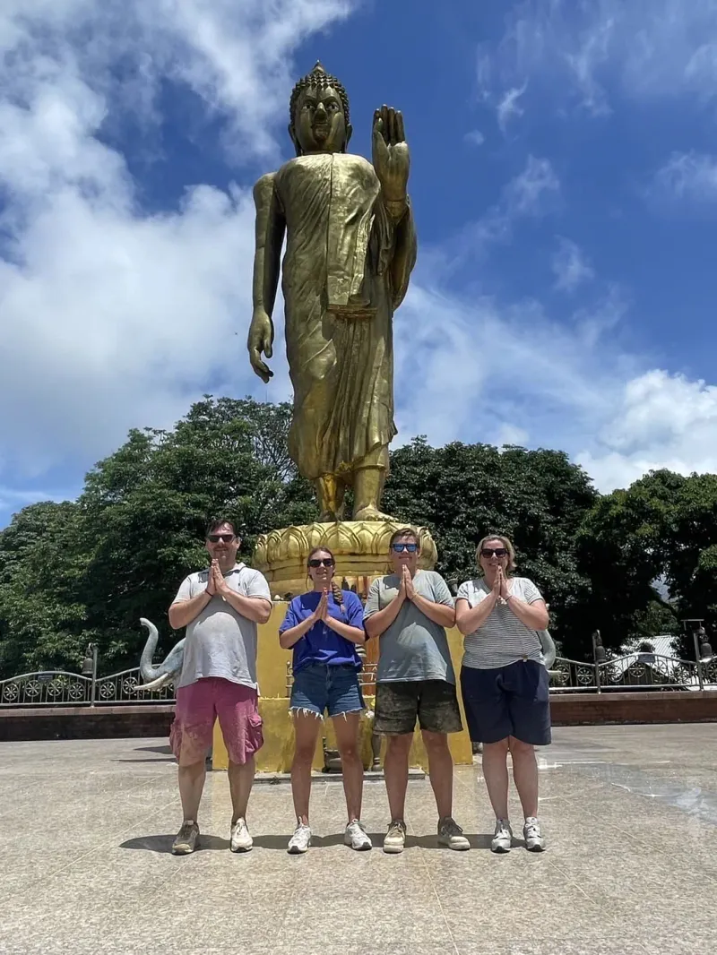 Visitors paying respects in front of the golden Buddha statue at Wat Teepangkorn