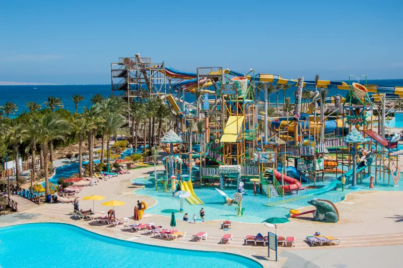 A colourful outdoor water park with slides and pools by the sea