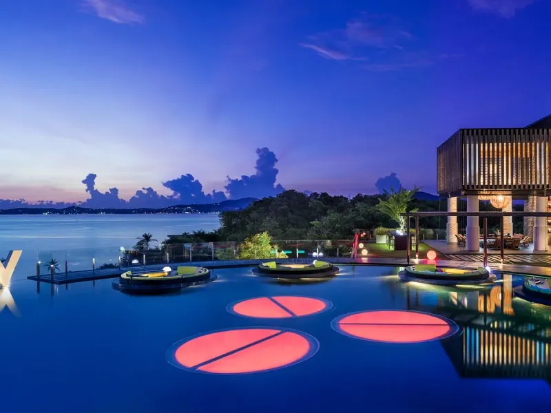 WOOBAR's illuminated pool platforms and glowing pink lily-pad lights on the infinity pool at night