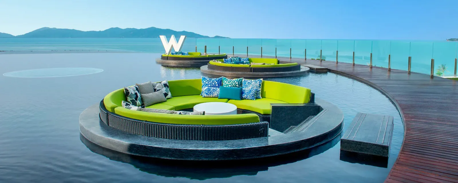 WOOBAR's circular green daybed on the pool by day, with the W Koh Samui sign and the Gulf of Thailand behind