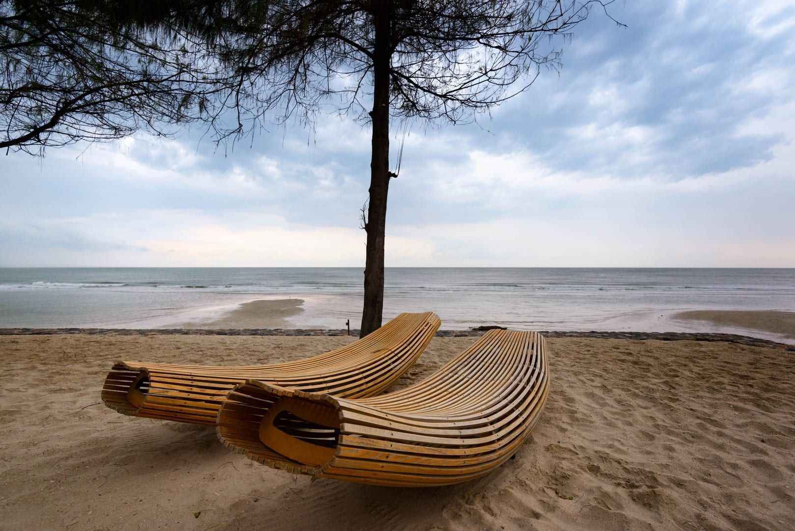 Wooden loungers under a shade tree overlooking the calm south coast of Koh Samui