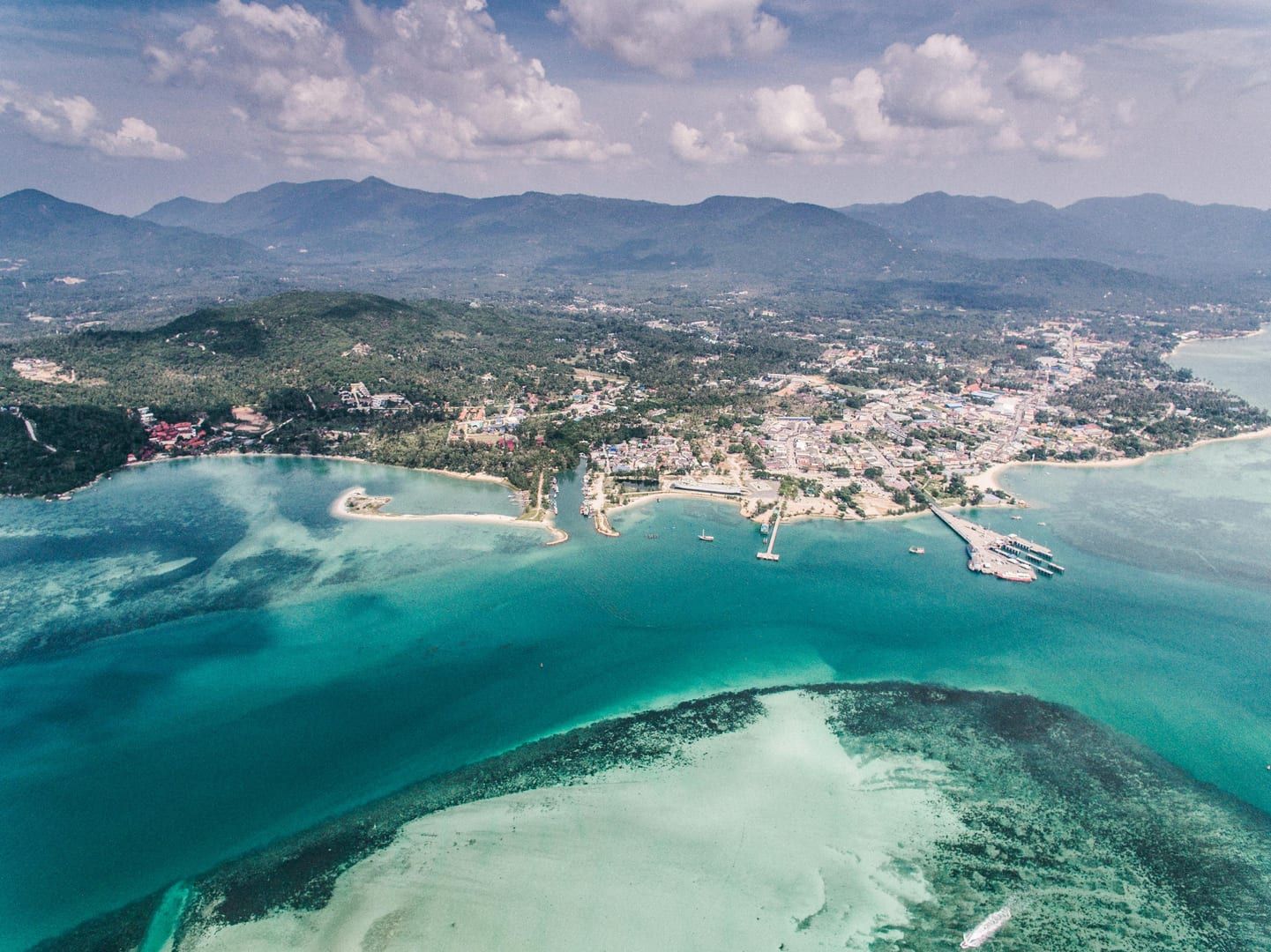 Aerial view of Koh Samui tropical coastal town with calm beach waters
