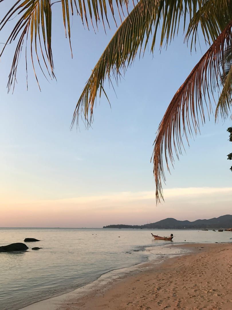 Longtail boat anchored on calm waters at sunset near Lipa Noi Beach
