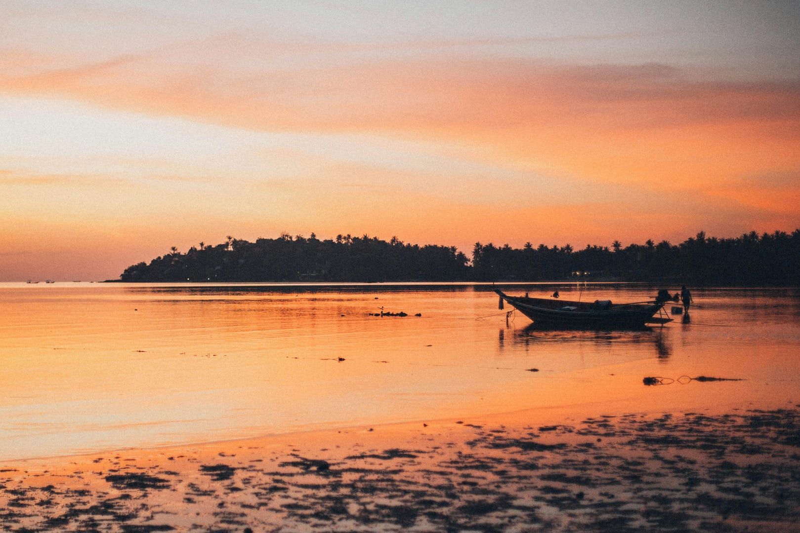 Silhouette of longtail boat at sunset on calm waters near Lipa Noi Beach Samui