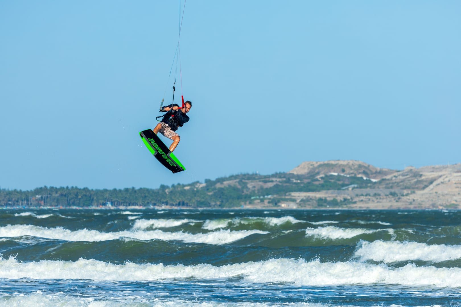 Kitesurfer launching into the air over the shallow waters of Na Khai Beach Koh Samui