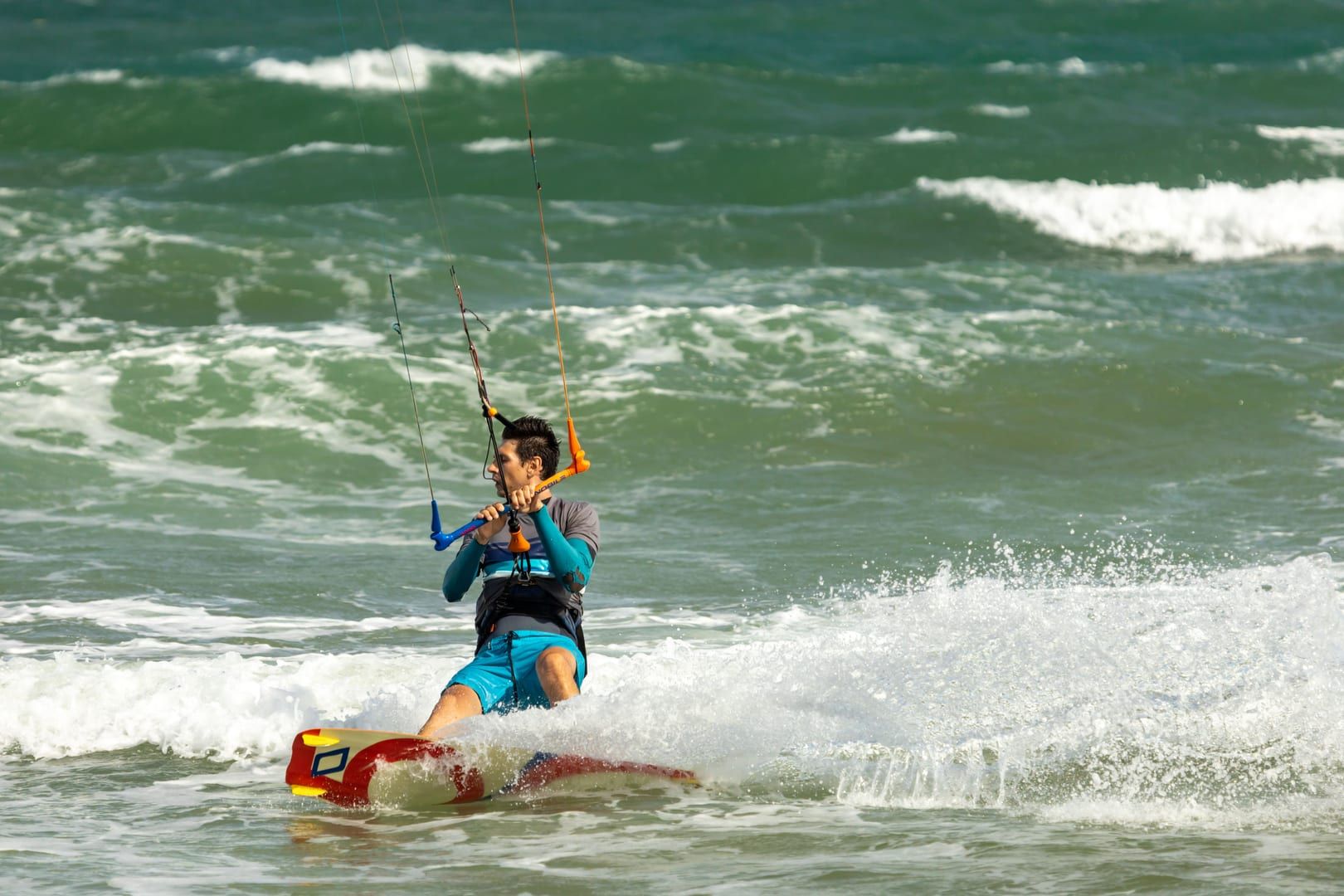 Kitesurfer creating spray while riding the shallow reef-protected lagoon at Na Khai Beach