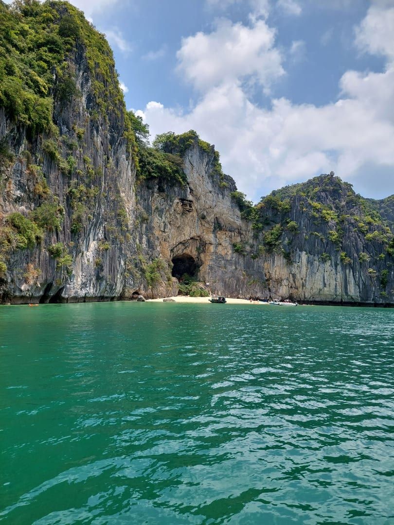Boat anchored near towering cliffs and emerald water close to Six Senses Samui
