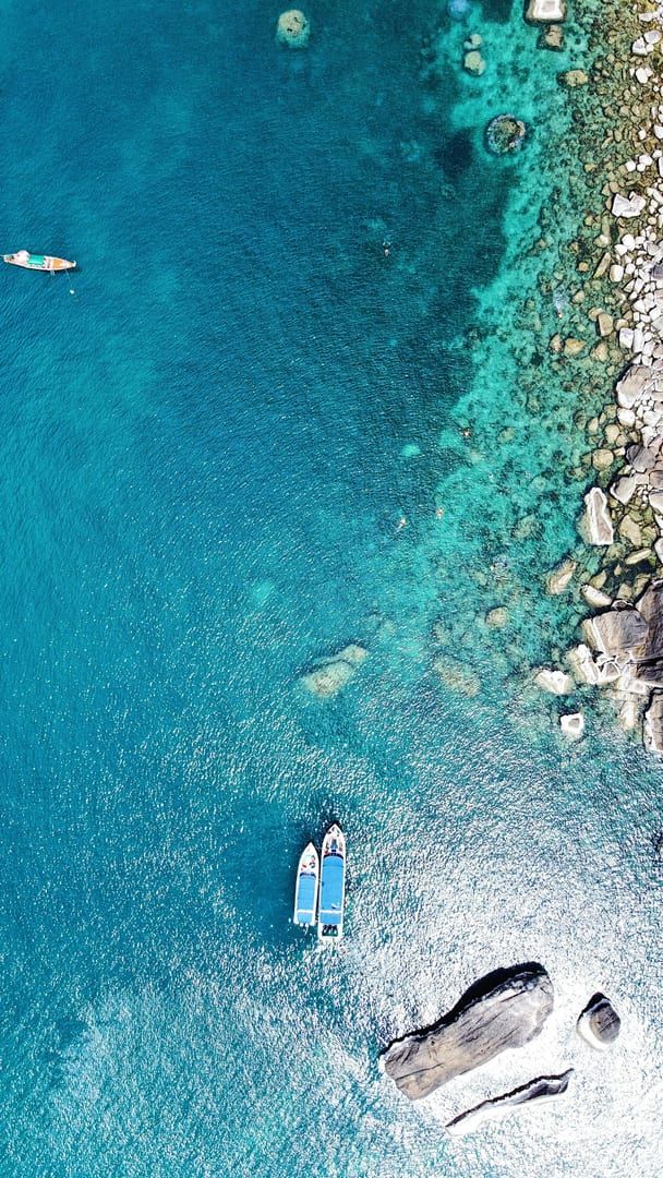 Aerial view of boats on turquoise Crystal Bay waters near rocky Samui shore