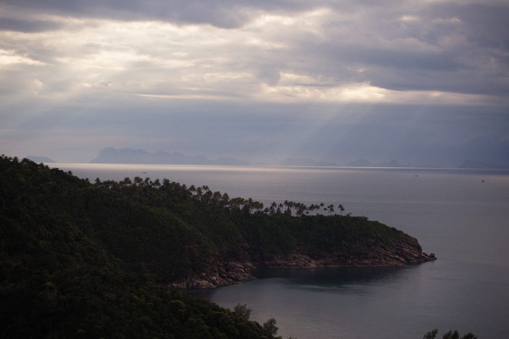 Panoramic view over jungle-covered coastline and hazy limestone islands from a hiking viewpoint in Ang Thong Marine Park
