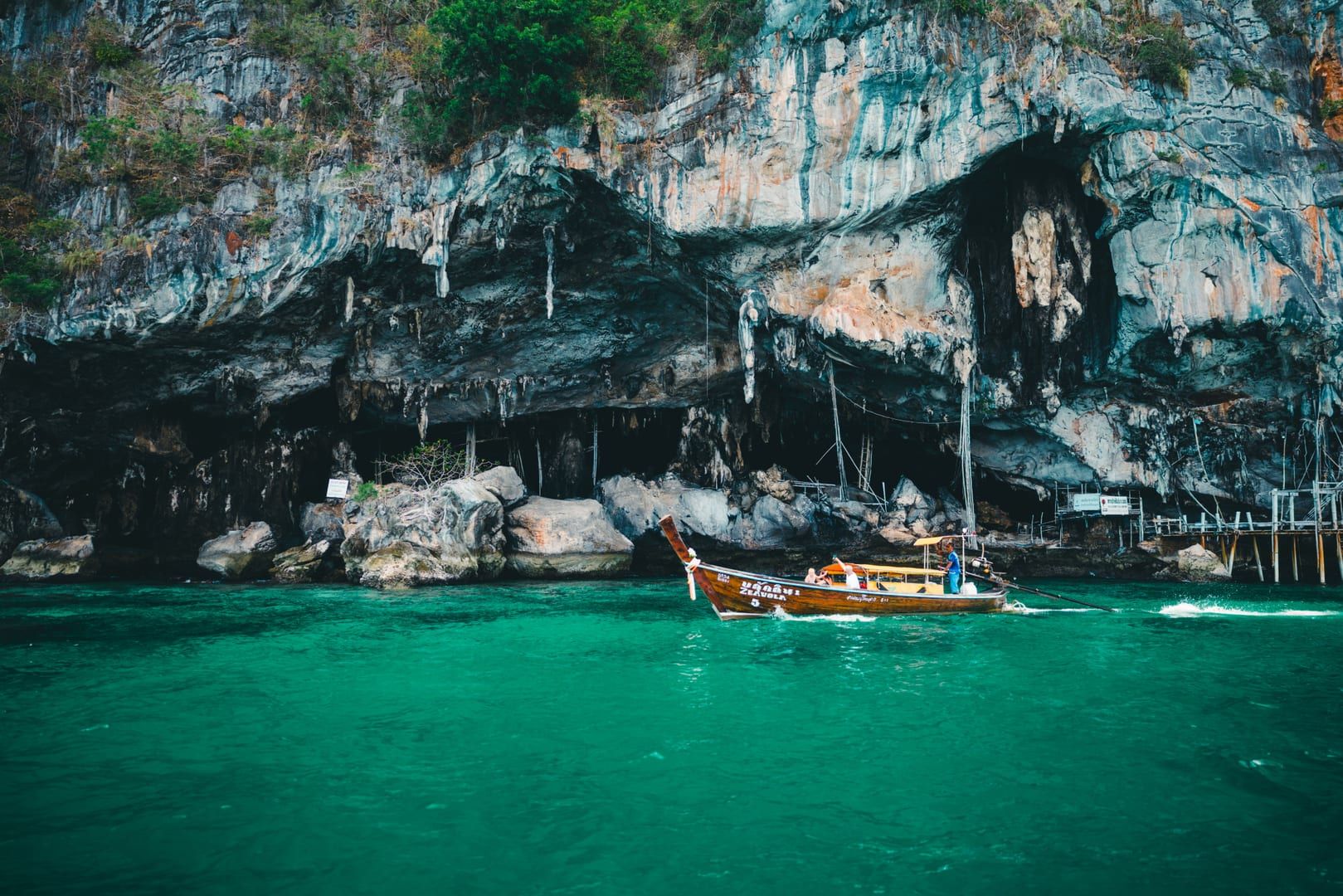 Traditional longtail boat passing a limestone sea cave near Ang Thong National Marine Park islands