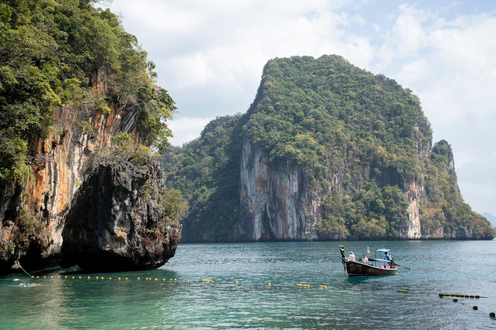 Towering limestone cliffs and a longtail boat inside Ang Thong National Marine Park near Koh Samui
