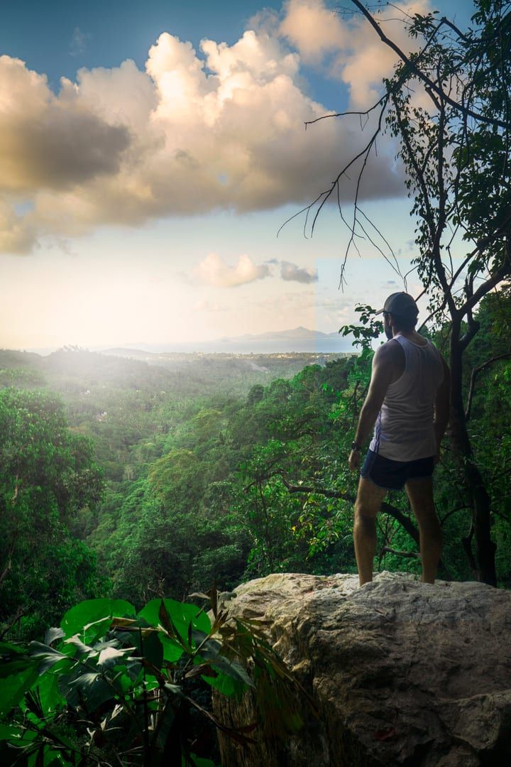 Hiker standing on a jungle cliff edge overlooking Koh Samui's highlands at the mountain restaurant viewpoint