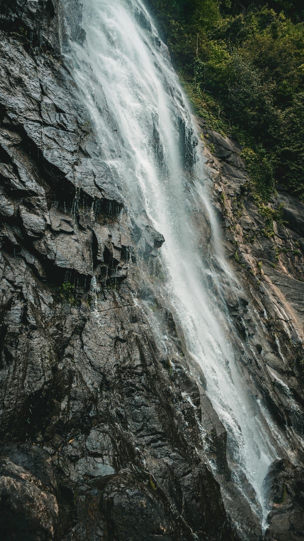 Tall waterfall cascading down rocky cliffs through jungle at Na Muang 2 Koh Samui